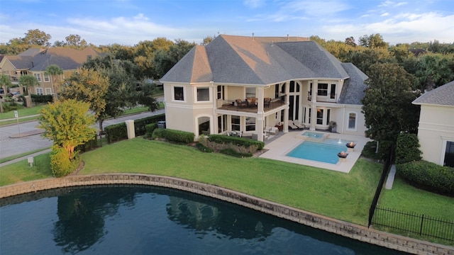 rear view of house with a balcony, fence, a yard, a fenced in pool, and stucco siding