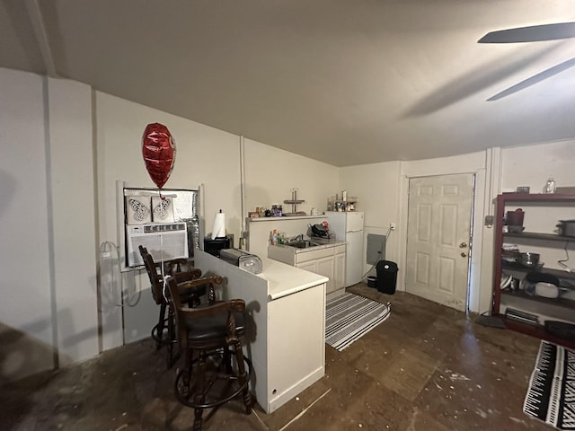 kitchen with freestanding refrigerator, cooling unit, a peninsula, concrete flooring, and a ceiling fan