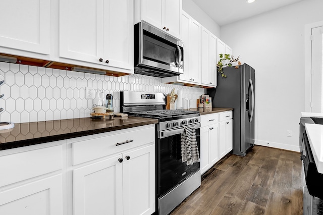 kitchen featuring dark wood-style floors, tasteful backsplash, dark countertops, appliances with stainless steel finishes, and white cabinets