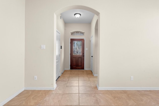 entryway featuring light tile patterned floors, baseboards, and arched walkways