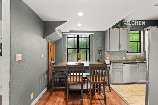 dining room with light wood-type flooring, a textured wall, baseboards, and recessed lighting