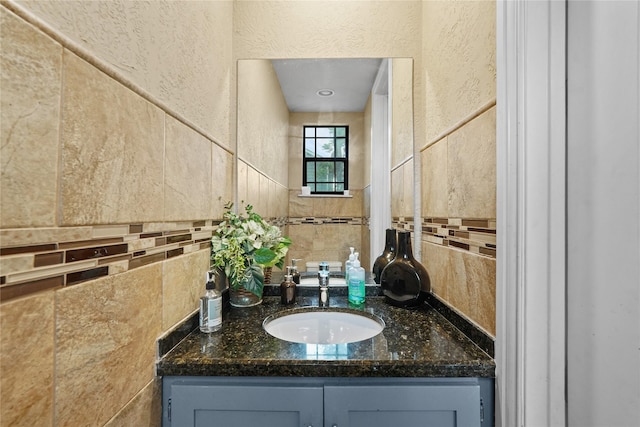 bathroom featuring a textured wall, vanity, and tile walls