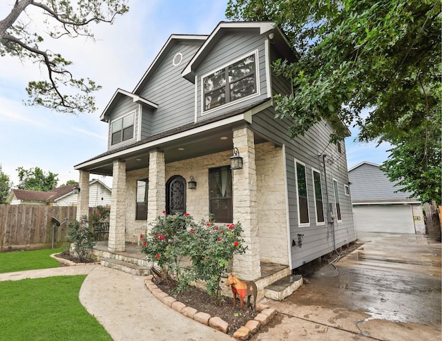 view of front of house featuring an outbuilding, covered porch, and fence