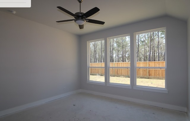 empty room with lofted ceiling, a healthy amount of sunlight, concrete floors, and baseboards