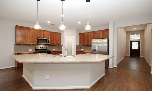 kitchen featuring brown cabinets, dark wood finished floors, tasteful backsplash, appliances with stainless steel finishes, and a sink