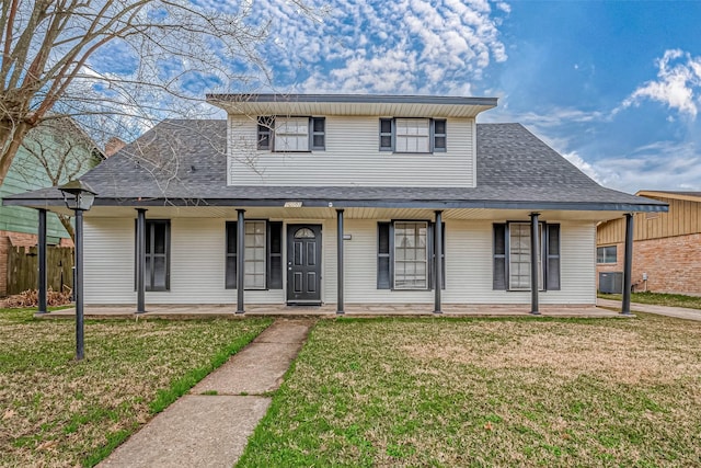 view of front facade with a shingled roof, a front yard, and fence