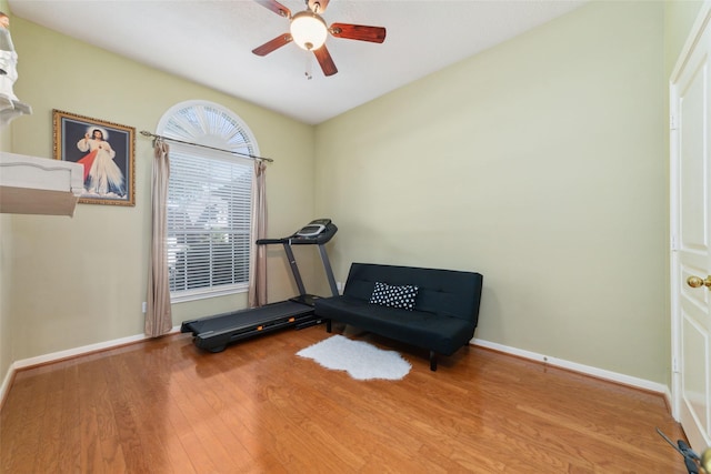 workout room with a ceiling fan, baseboards, and wood finished floors