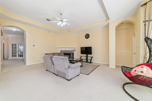 living room featuring arched walkways, light colored carpet, visible vents, a high end fireplace, and decorative columns