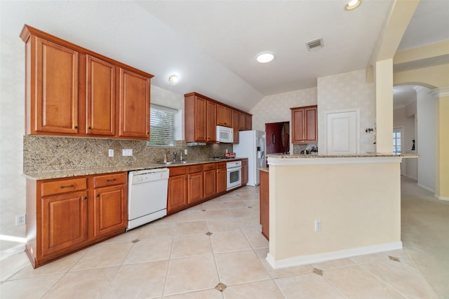 kitchen with brown cabinets, white appliances, and visible vents