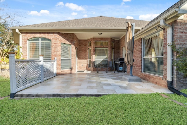 rear view of house with brick siding, a yard, and a patio