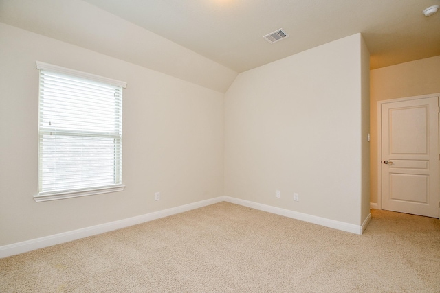 carpeted empty room with baseboards, visible vents, and vaulted ceiling