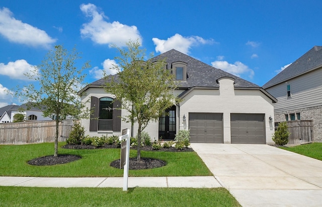 french country style house featuring fence, an attached garage, a front lawn, concrete driveway, and brick siding