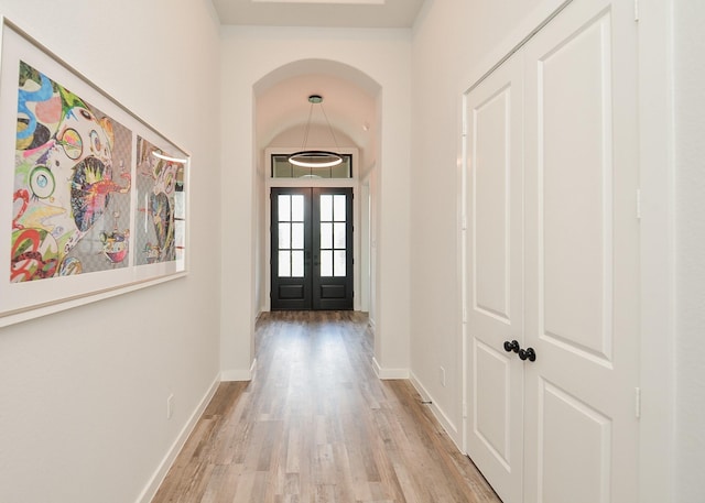 interior space featuring wood finished floors, french doors, baseboards, and arched walkways