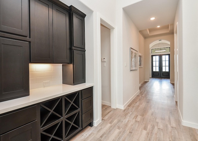 corridor with a raised ceiling, recessed lighting, baseboards, and light wood-type flooring