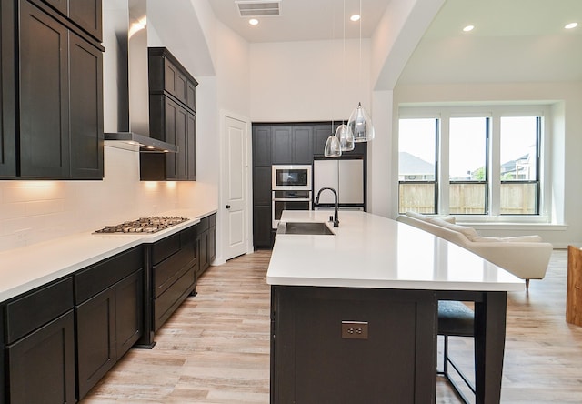 kitchen featuring visible vents, a kitchen breakfast bar, backsplash, appliances with stainless steel finishes, and wall chimney range hood