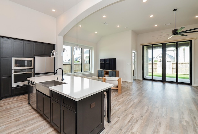 kitchen featuring a ceiling fan, a sink, open floor plan, arched walkways, and built in appliances