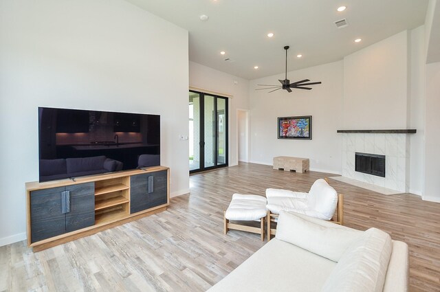 living room featuring baseboards, wood finished floors, ceiling fan, and a fireplace