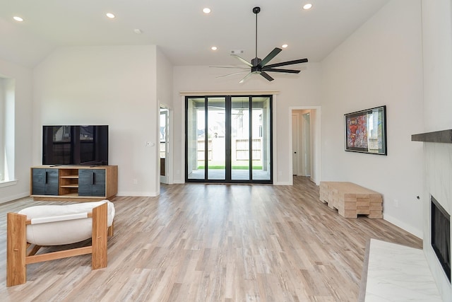 living room with baseboards, ceiling fan, a fireplace with flush hearth, recessed lighting, and light wood-style floors