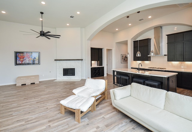 living room featuring visible vents, ceiling fan, a high end fireplace, and light wood finished floors