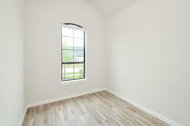 unfurnished room with baseboards, lofted ceiling, and light wood-style floors