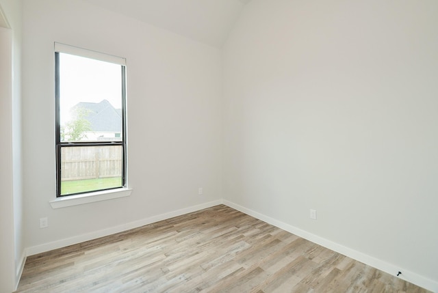 unfurnished room featuring lofted ceiling, wood finished floors, and baseboards