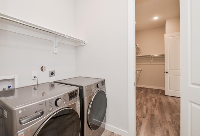 laundry room featuring laundry area, wood finished floors, baseboards, and washer and clothes dryer