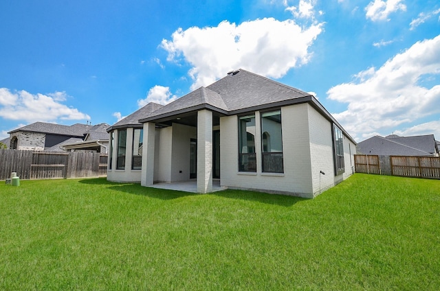 rear view of property featuring brick siding, a patio area, a lawn, and a fenced backyard