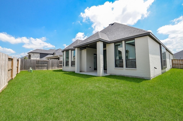 rear view of house with brick siding, a lawn, a patio, and a fenced backyard