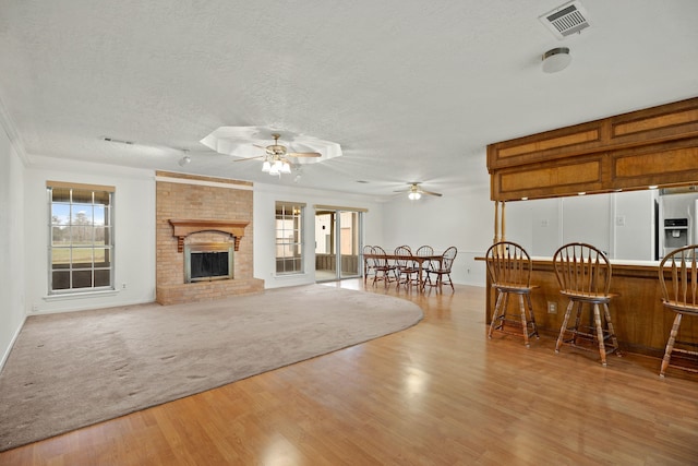 living room with light wood-style floors, a healthy amount of sunlight, visible vents, and a textured ceiling