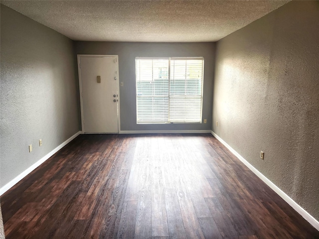 unfurnished room with baseboards, a textured wall, and wood finished floors