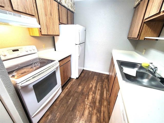 kitchen featuring white appliances, baseboards, dark wood-type flooring, under cabinet range hood, and a sink