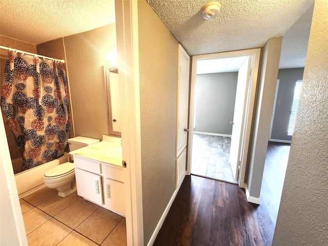 bathroom featuring a textured ceiling, a textured wall, and wood finished floors