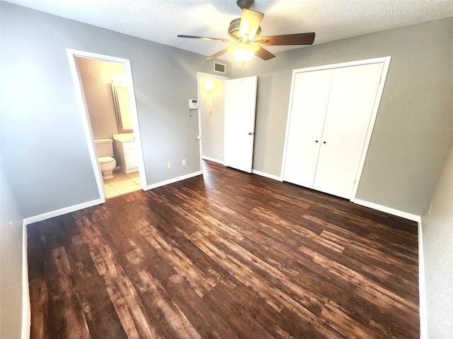 unfurnished bedroom with visible vents, a closet, wood finished floors, baseboards, and ceiling fan