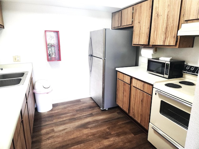 kitchen featuring range hood, light countertops, brown cabinets, a sink, and appliances with stainless steel finishes