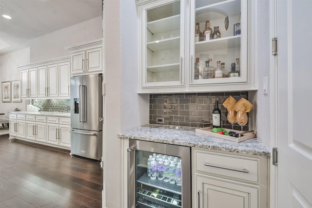 kitchen with wine cooler, light stone counters, high end refrigerator, dark wood finished floors, and glass insert cabinets