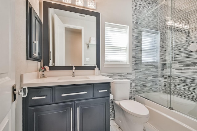 bathroom with toilet, enclosed tub / shower combo, visible vents, and vanity