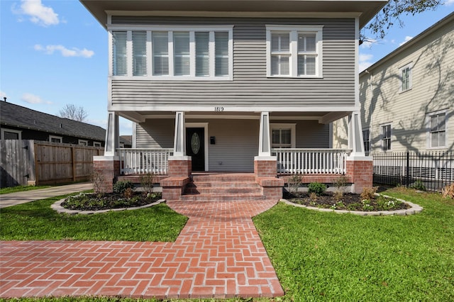 view of front of house featuring a porch, a front lawn, and fence