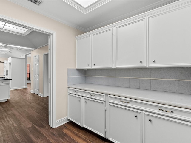 kitchen with white cabinets, light countertops, ornamental molding, backsplash, and dark wood-style floors