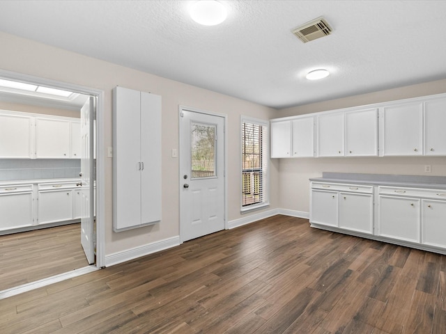 kitchen with light countertops, white cabinets, dark wood finished floors, and visible vents