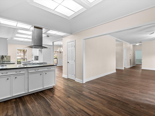 kitchen featuring island range hood, stainless steel gas cooktop, white cabinets, dark countertops, and dark wood finished floors