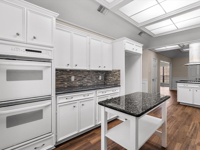 kitchen with dark wood-style flooring, white double oven, visible vents, white cabinets, and dark stone counters