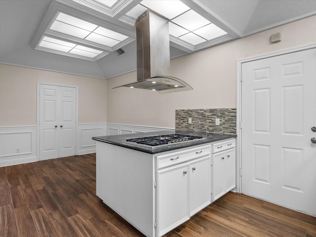 kitchen with island exhaust hood, dark countertops, stainless steel gas stovetop, dark wood-type flooring, and white cabinetry