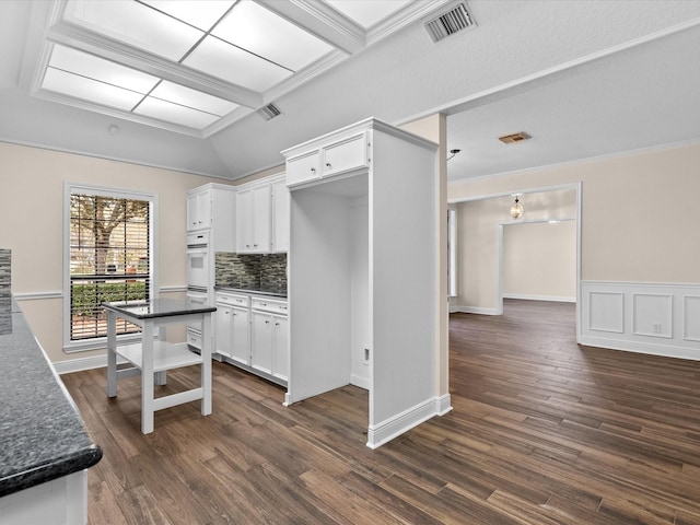 kitchen with visible vents, white cabinetry, dark wood finished floors, and backsplash