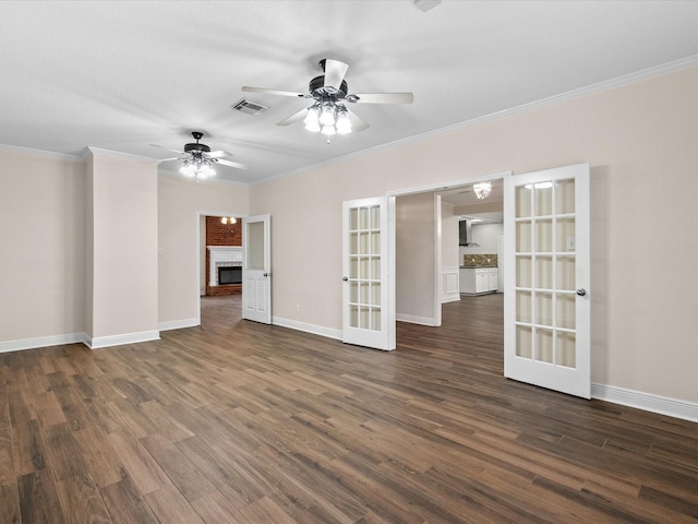 empty room with visible vents, ornamental molding, french doors, a brick fireplace, and dark wood finished floors