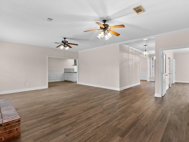 unfurnished living room featuring dark wood-style flooring, a ceiling fan, visible vents, baseboards, and ornamental molding