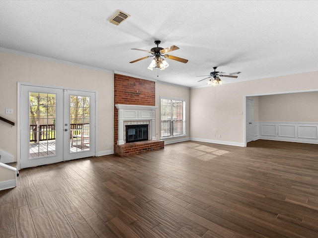 unfurnished living room with a brick fireplace, visible vents, dark wood finished floors, and a textured ceiling