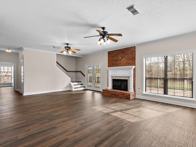 unfurnished living room with visible vents, dark wood-type flooring, ornamental molding, a brick fireplace, and baseboards