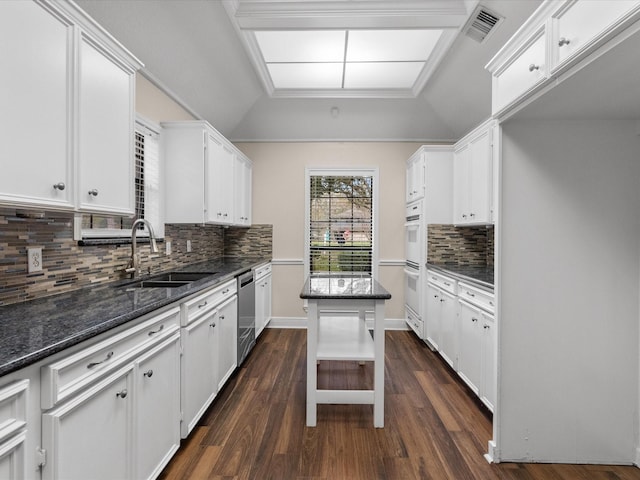 kitchen with white cabinets, a sink, visible vents, and dark stone countertops