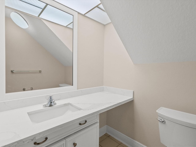 half bath featuring baseboards, toilet, tile patterned flooring, vaulted ceiling, and vanity