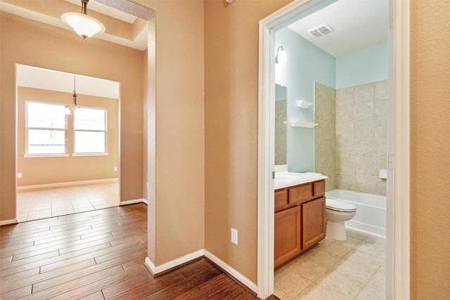 bathroom featuring toilet, shower / bath combination, visible vents, vanity, and baseboards